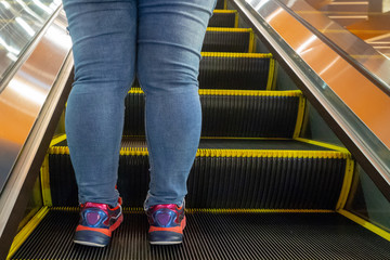 women leg standing on escalator