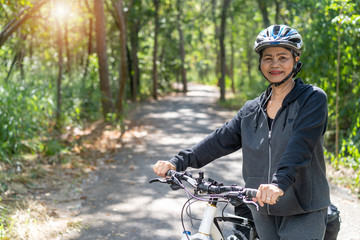 Naklejka premium Attractive senior asian woman with bicycle in park