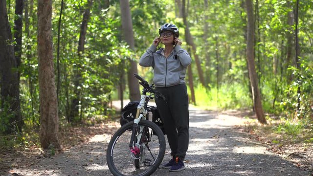 Attractive senior asian woman wearing a helmet with bicycle in park