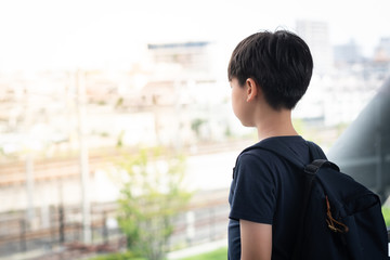Portrait, Good looking Asian tween student boy stand alone, isolated, lost in thought on walkway at school. Bullying, Teen problems, Physical and emotional abuse, Loneliness, Withdrawn, Introvert.