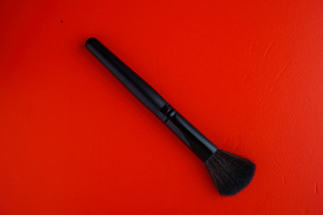 Top view of black make up brush on red backround.