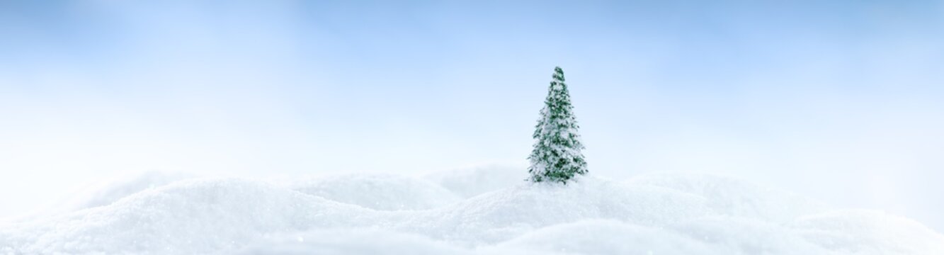 Wintery landscape background with single tree on glistening white snow drifts