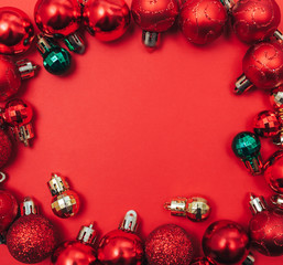 Red Christmas balls frame on red background with copy space in centre. Flat lay.