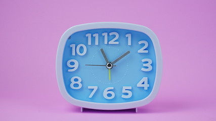 Blue Alarm clock face beginning of time 11.00 am or pm on pink background.