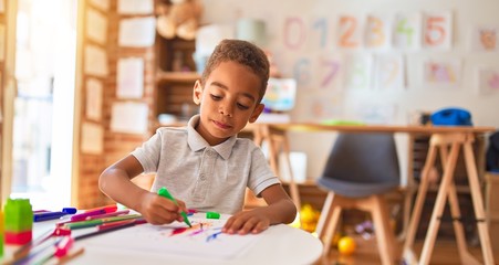 Naklejka premium Beautiful african american toddler drawing using paper and marker pen at kindergarten