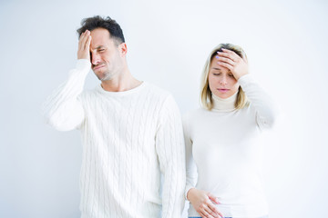 Young beautiful couple wearing casual t-shirt standing over isolated white background suffering from headache desperate and stressed because pain and migraine. Hands on head.