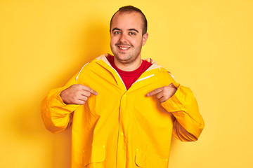 Young man wearing rain coat standing over isolated yellow background looking confident with smile...