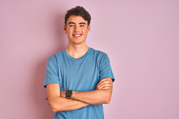 Teenager boy wearing casual t-shirt standing over blue isolated background happy face smiling with crossed arms looking at the camera. Positive person. - obrazy, fototapety, plakaty
