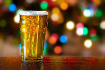 Pint of beer with christmas tress lights on the background
