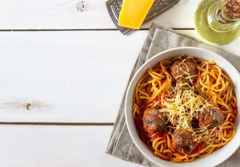 Pasta with meatballs and tomato sauce on a wooden background.
