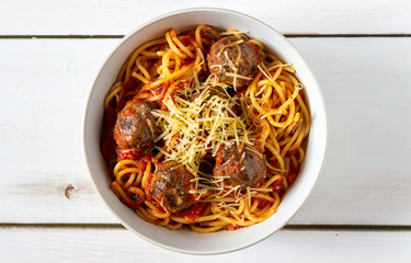 Pasta with meatballs and tomato sauce on a wooden background.