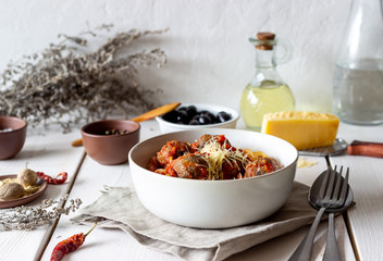Pasta with meatballs and tomato sauce on a wooden background.
