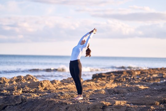 Young beautiful sportwoman practicing yoga. Coach teaching mountain pose at the beach