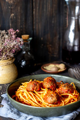 Pasta with meatballs and tomato sauce on a wooden background.