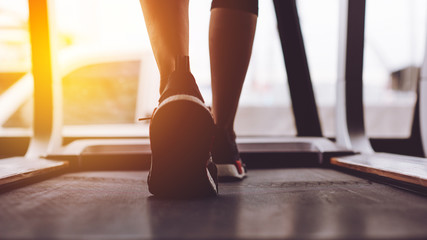 Close up shoes woman's muscular legs feet running on treadmill workout at fitness gym.
