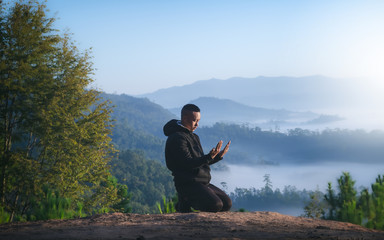 Naklejka na ściany i meble Man worship and praying at morning on mountains with nature landscape. Christian concept.