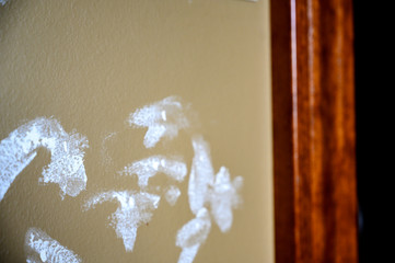 Drywall repair with white putty filler ready for paint