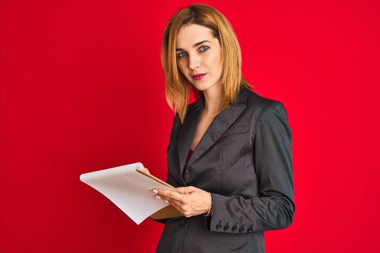 Young beautiful redhead businesswoman wearing suit writing on flip board