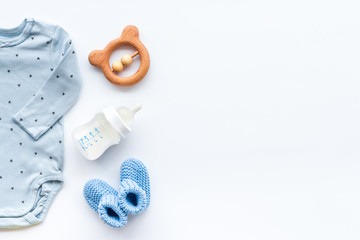 Newborn baby boy set - blue clothes as bodysuit, booties, toys - on white table top-down frame copy space