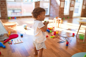 Adorable toddler playing around lots of toys at kindergarten