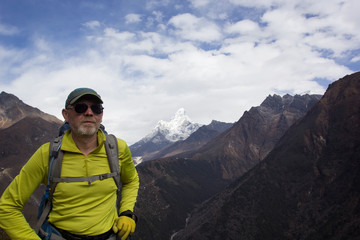 Male tourist with a backpack in the mountains. Himalayas, Nepal. In the background is AMA Dablam,...