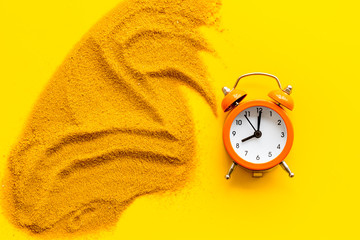 Deadline concept. Clock near sand on yellow background top-down