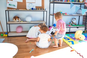 Adorable toddlers playing around lots of toys at kindergarten