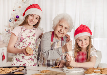 Grandmother with granddaughters soak cream decorating cookies with cream
