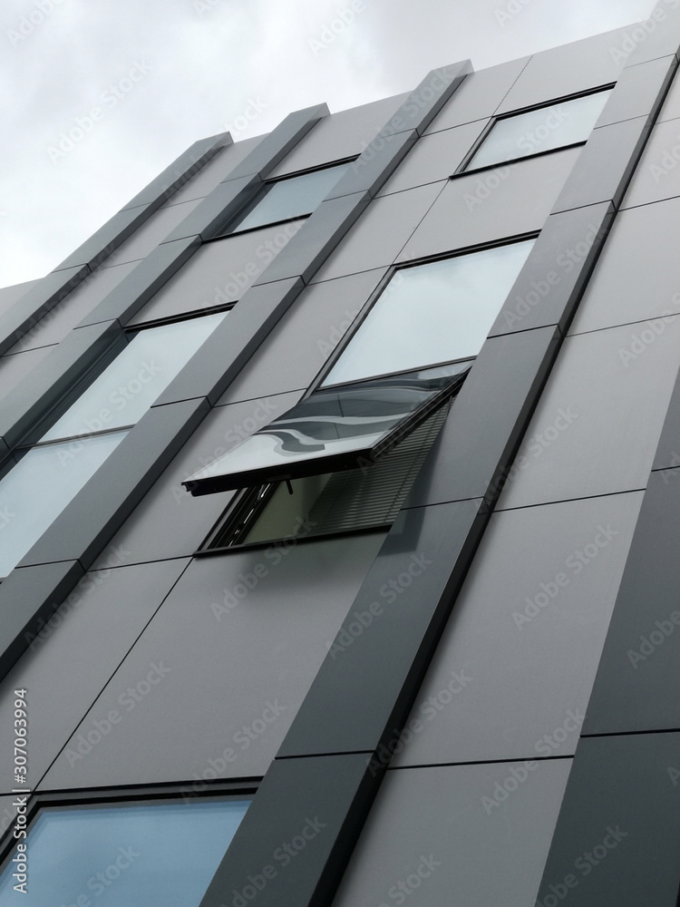 Poster close-up photo of windows and wall panels. fragment of industrial building exterior with ajar window