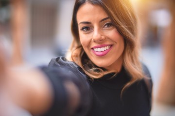 Young beautiful woman smiling happy and confident. Standing make selfie by camera at town street