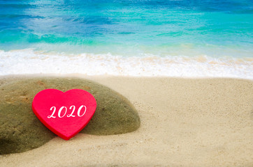 Fototapeta premium Symbol from number 2020 on the big heart on the sandy beach