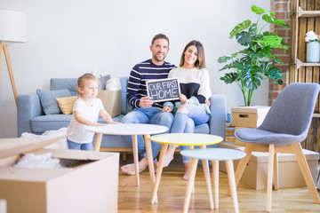 Beautiful famiily with kid sitting on the sofa holding blackboard at new home around cardboard boxes