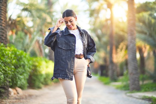 Young beautiful woman wearing denim jacket smiling happy and confident. Standing with smile on face at the town park