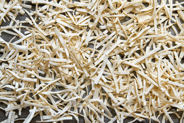 Handmade noodles are dried on a wooden board. Top view