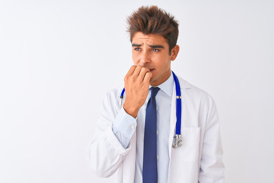 Young handsome doctor man wearing stethoscope over isolated white background looking stressed and nervous with hands on mouth biting nails. Anxiety problem.