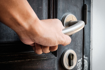 Hand opening a wooden door