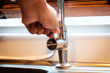 Hand opening a water faucet