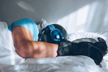 man in bed with snowboard ski googles and helmet