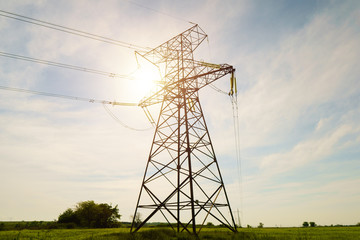 Electrical net of poles on a panorama of blue sky and green meadow