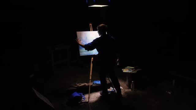 Artist copyist paint seascape with ship in ocean. Craftsman decorator draw as boat sail on blue sea with acrylic oil color. Black background. Indoor. Wide angle shot cinematic look.