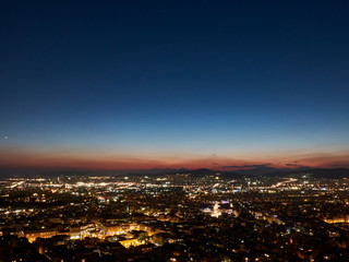 Fototapeta premium City panorama at sunset. Dusk landscape with city, mountains and clouds in the rays of setting sun. Athens, Greece