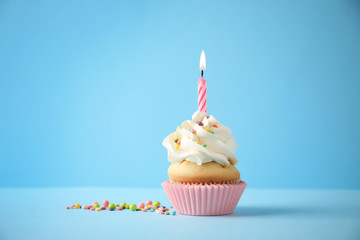 Delicious birthday cupcake with candle on light blue background