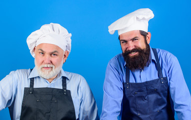 Cafe workers. Restaurant kitchen. Culinary industry. Restaurant staff. Father and son culinary hobby. Family restaurant. Mature bearded men professional restaurant cooks. Chef men wear aprons