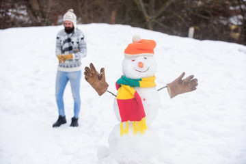 Our traditions. winter holiday outdoor. warm sweater in cold weather. man play with snow. happy hipster ready to celebrate xmas. bearded man build snowman. winter season activity. its christmas