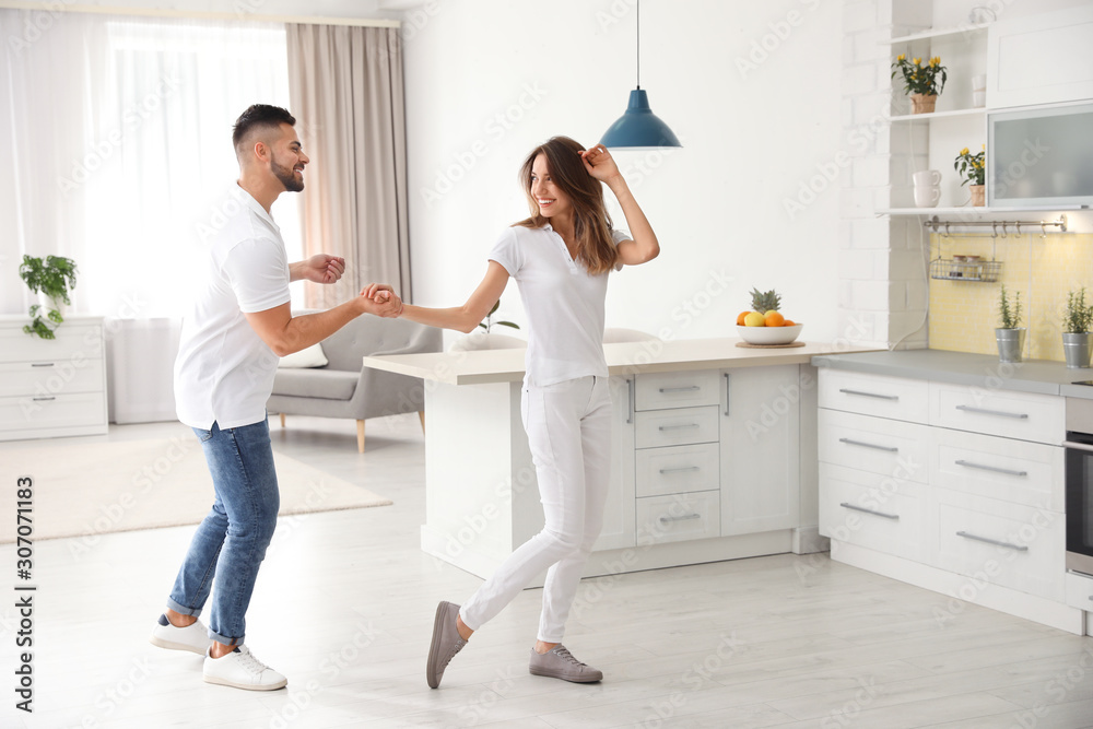 Sticker Lovely young couple dancing in kitchen at home