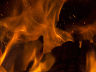 Primal bewitching magic of fire. Dance of orange flames on charred logs. Bonfire burning with...