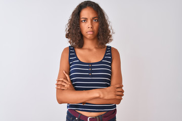 Young brazilian woman wearing striped t-shirt standing over isolated white background skeptic and nervous, disapproving expression on face with crossed arms. Negative person.