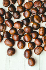 Vertical image of raw chestnuts thrown on a white background.