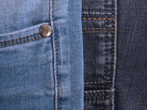 Jeans background. Blue denim texture with pocket, seams and stitches. Denim pile. Dark and light blue jeans.