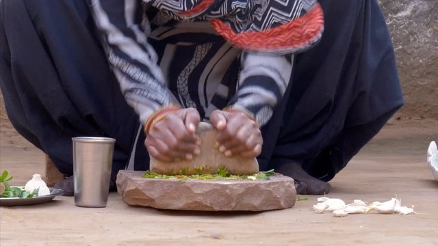 Indian housewife making chutney using a stone grinder / sil batta. HD video of Indian housewife is preparing chutney using a sil batta